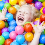Blond Girl Child Having Fun Playing in Colored Balls